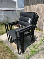 Stack of four black metal mesh outdoor chairs
