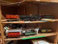 Shelves with multiple O27 gauge train cars, locomotive, books