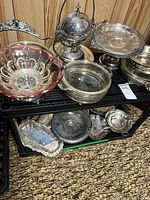 Multiple silver-plated dishes and trays on shelving