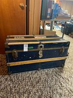Front view of navy blue trunk showing latches, lock, wood slats