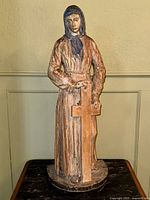 Full frontal view of the carved wood statue showing overall form and posture