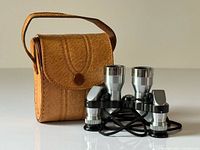 opera glasses standing beside leather case