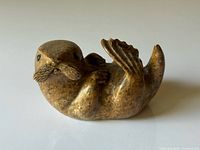 Front view of brown soapstone seal figurine on its back with raised flipper