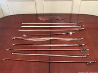 Nine violin bows, chinrest, loose hair and detached frog on table