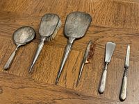 All six Birks sterling vanity pieces laid out: round mirror, hairbrush, rectangular mirror, button hook, shoehorn, nail file