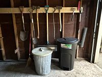 Overall lot showing shovels, axes, broom and two trash cans
