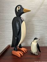 Large and small carved wood penguins front view