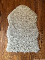 Full view of faux sheepskin rug on wood floor