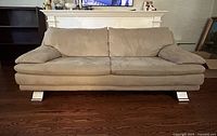 Front view of beige ultrasuede sofa showing overall style and legs