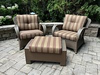 Two resin wicker chairs and ottoman with cushions, front view