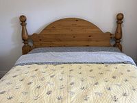 Front view of queen pine cannonball headboard attached to bed