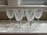 Front view of eight crystal wine glasses showing Lismore cut pattern and star bases