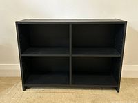 Front view of black bookshelf showing four open cubbies