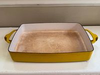 Top view of yellow enamel cast iron baking dish showing worn interior