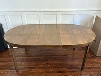 Front view of oval walnut dining table with centre leaf inserted