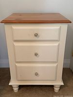 Front view of three-drawer painted pine bedside table