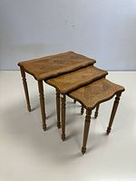 Three wooden parquet style nesting tables nested in decreasing size order, showing wood pattern and turned legs