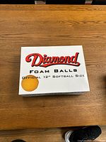 Top view of a white box labeled 'Diamond Foam Balls' with 'Official 12'' Softball Size' text and an image of a yellow softball.