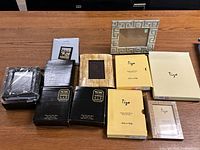 All frames including Tigo brand frames and other various black and silver tone frames on wooden table