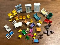 Full overview of 38 small assorted toy furniture pieces including beds, chairs, tables, cabinets, and benches in various colors and styles, laid out on a wooden floor.