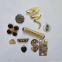 Group of small accessories including brooches, pins and money clips displayed on white background.