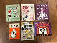 Top view of six comic character books showing front covers arranged on wood floor for identification.