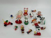 Group of various Peanuts character toys and figurines including Snoopy, Woodstock, and Charlie Brown in assorted poses and styles.