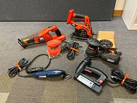 Group of five power tools on carpet floor showing all items in lot.
