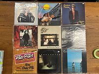 Top view of nine vintage vinyl LPs arranged in a 3x3 grid showing various artists and album cover art.