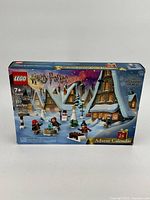 Front view of the unopened Harry Potter LEGO Advent Calendar box showing festive Hogwarts-themed scene with mini-figures and snow-covered buildings.