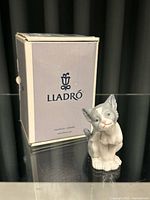Porcelain cat figurine next to original Lladro box showing front view.