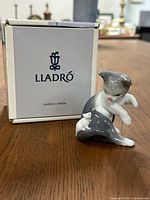 Figurine and original box displayed on a table, showing front view of the cat figurine, mostly gray and white with the Lladro box behind it with logo.