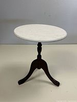 Full side view of the marble top accent table showing the circular marble top and dark wooden tripod base with three legs and central turned column support.