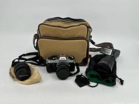 Full lot showing the camera with attached lens, two additional lenses (one with flash), and carrying bag.