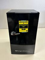 Front view of black Frigidaire personal refrigerator with chrome handle and Energy Guide label.
