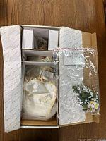 Top-down view of the doll inside original box showing doll wrapped in plastic with separate accessory packages beside it