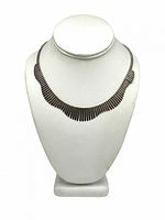 Front view of the segmented wavy sterling silver necklace displayed on a white bust form showing the necklace's shape and segment pattern.