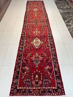 Full length of the red Hamadan runner on white tile floor