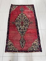 Top view of the rectangular Hamadan Persian rug showing red central field with diamond medallion and decorative corners