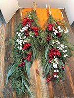 Two holiday swags laid flat showing full length, foliage and berry accents