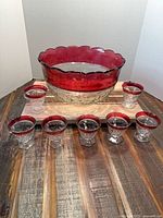 Punch bowl and seven matching cups displayed on wooden board