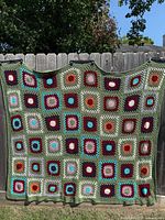 Front view of full crocheted afghan hanging on fence