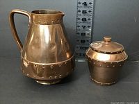 Front view of pitcher and lidded bowl with scale