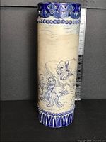 Full view of cylindrical vase showing incised lions and decorative bands with ruler for scale