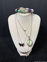 Full group view on display bust showing bracelet on top, three chains with pendants, and ring