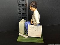 Front view of figurine showing architect with model and blueprint