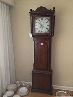 Full view of grandfather clock next to dishes for scale