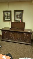 Front view of closed wooden stereo console with lid partly open