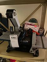 Full view of Delta ShopMaster grinder/sander with extra discs on shelf