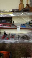 overview of shelf with socket set, drill attachment, gear puller, plier set, clamps visible